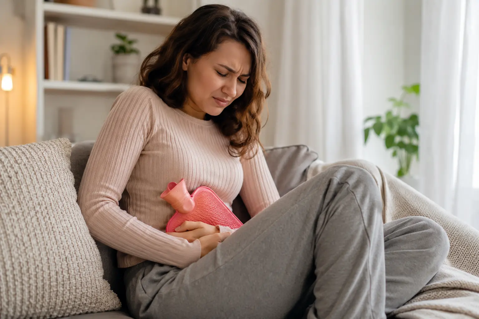 Femme assise tenant une bouillotte, illustrant un mal de ventre lié à l'endométriose.